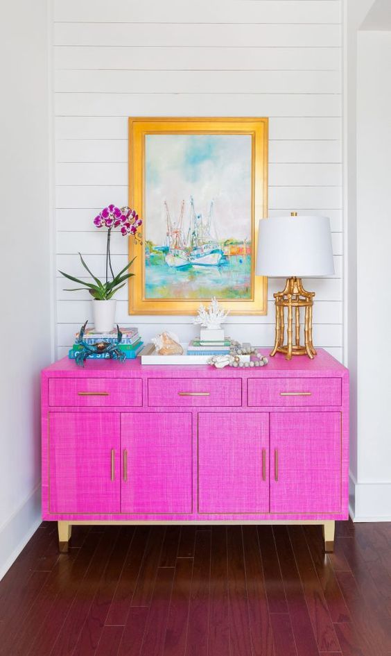 A jaw dropping hot pink grasscloth paper sideboard with gold legs and bright decor will make a statement with color and texture