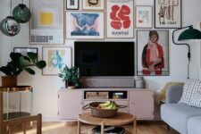 57 a fantastic living room with a colorful gallery wall, a pink TV unit, a grey sofa, wooden chairs and a coffee table, pendant lamps