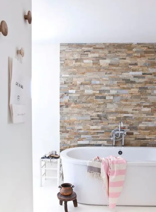 an earthy colored faux stone accent wall is a gorgeous way to spruce up a neutral contemporary bathroom