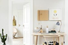 a Scandi working space with a light-stained dining table, a matching wishbone chair, a mini gallery wall and some decor