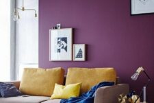 a Scandinavian living room with a purple accent wall, a beige sofa with yellow pillows, a side table, a printed rug and geo artwork