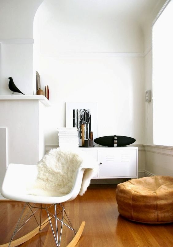 a Scandinavian nook with a locker, a white Eames rocker, a faux fur cover, a brown pouf and some pretty decor