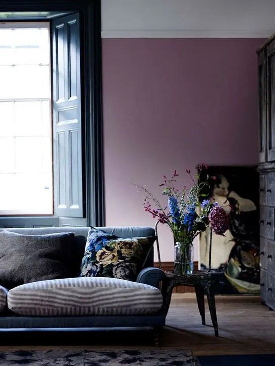 a beautiful living room with a purple accent wall, a navy and grey sofa, a pretty artwork and a vintage sideboard is a gorgeous space