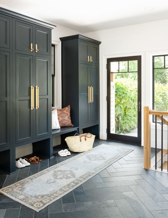 A black and white mudroom in farmhouse style, with large wardrobes, a built in bench, a printed rug and a glass door