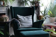 a bold boho nook with a dark green Strandmon wingback chair and a matching footrest, lots of greenery, cacti and artworks