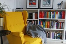 a bold reading nook with bookcases, a yellow Strandmon chair, a cool table lamp, a side table and a grey blanket