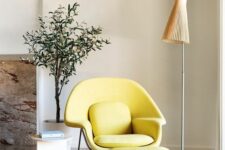 a bright and chic nook with a bold yellow Wumb chair and ottoman, a side table, a floor lamp and a potted plant