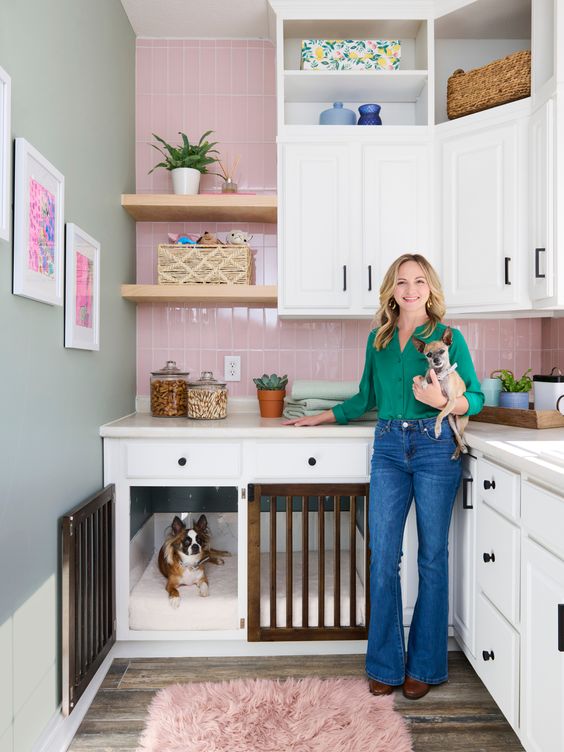 A catchy pink and white kitchen with shaker cabinets and built in dog kennels is a cozy and cute space