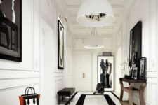 a chic black and white entrance with white walls and a marble floor, artworks and a mirror in a frame, black leather benches