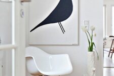 a chic styled awkward nook with a white Eames rocker, a black and white artwork and a vase with white blooms