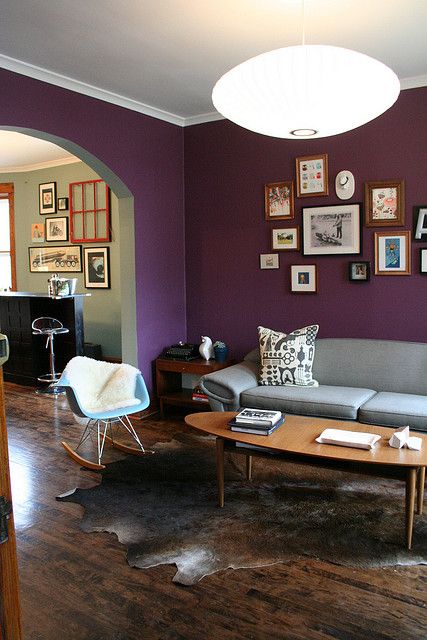 a classy purple living room with a grey sofa, an oval table, a rocker chair and a gallery wall is chic and stylish