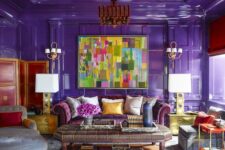 a colorful living room with a red ceiling, purple walls, a purple sofa, a grey daybed and a chair, a bold chandelier and a large coffee table