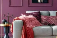 a colorful living room with purple molded walls, a grey sofa, a coffee table, an elegant side table and bold textiles