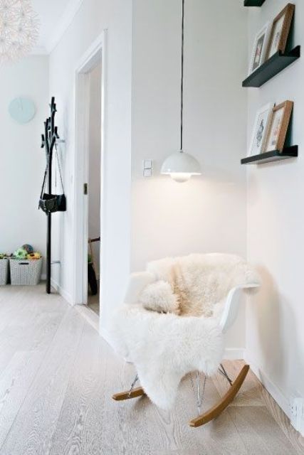 a cozy Scandinavian space with black ledges for gallery walls, a white Eames rocking chair with faux fur, a white pendant lamp