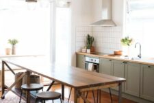 a cozy mid-century modern kitchen with lower olive green cabinets, a vintage wooden kitchen island, wooden stools and vintage pendant lamps