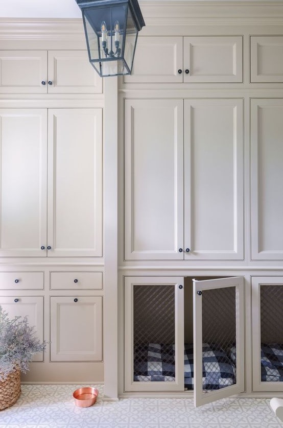 A creamy mudroom with shaker style cabinets and lower cabinets with built in dog crates is a cozy and cool space