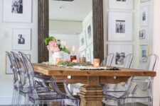 a farmhouse dining room with a stained rustic dining table, ghost chairs, a chic chandelier and photos all over the walls