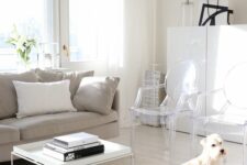 a light-filled living room with a greige sofa, a white coffee table, ghost chairs, a white storage cabinet and black touches