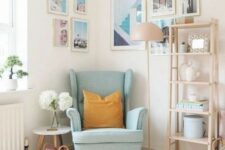 a light-filled nook with a blue Strandmon chair, a side table, a light-stained shelving unit, a gallery wall on two walls