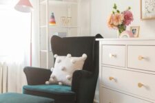 a little nook in the kid’s room with a dark green Strandmon chair and a matching ottoman, a dresser and a shelving unit in the corner