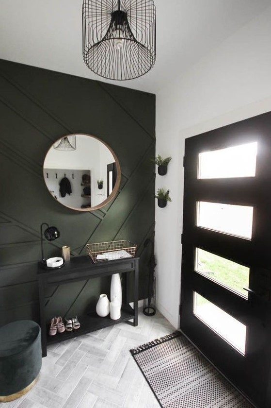 a modern farmhouse entryway with a black accent wall, a black console and a door, a dark green pouf and a printed rug