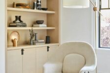 a neutral space with a light-stained built-in storage unit, a creamy Wumb chair, a side table and a floor lamp