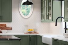 a refined olive green kitchen with glass and shaker cabinets, white and black countertops, a white scale tile backsplash and black handles