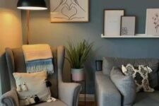 a relaxing Scandinavian living room with a blue accent wlal, a grey sofa and a Strandmon chair, printed textiles and a ledge with a gallery wall