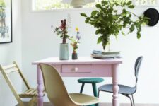 a small dining nook with a pink vintage table, mismatching pastel chairs, some greenery and blooms and a neutral pendant lamp