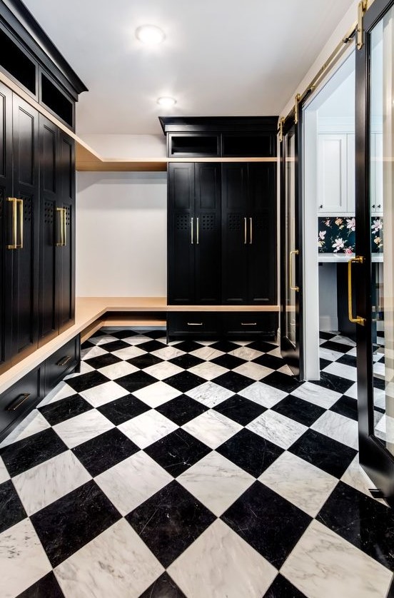 a stylish and elegant black and white mudroom with black wardrobes, a stained bench and a black and white marble floor
