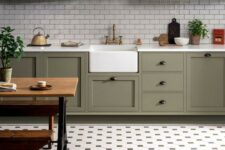 a stylish farmhouse olive green kitchen with white subway tiles and a pretty tile floor plus a rustic dinign set is wow