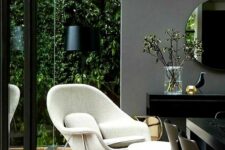 a stylish glazed dining space with a glazed roof and walls, moody black furniture and a creamy Wumb chair for a contrast