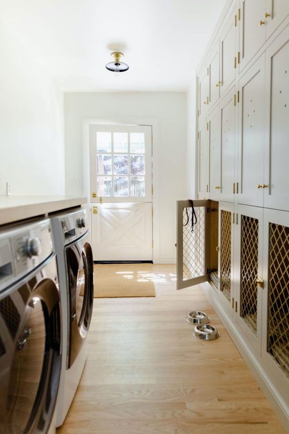 a stylish neutral mudroom with profiled cabinets and built-in dog crates plus a washing machine and a dryer opposite the cabinets