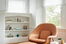 a stylish nook with a built-in shelving unit, an amber leather chair and ottoman, a side table and a rug us cozy and cool