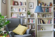 a stylish reading space with bookcases, a grey Strandmon chair and an ottoman, a blue floor lamp and some greenery