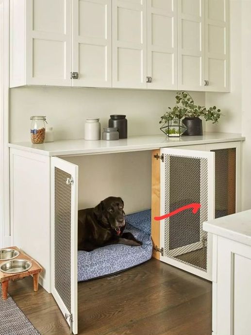 A stylish white farmhouse kitchen with profiled cabinets and a built in dog kennel in the lower part is a cool solution
