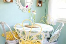 a vintage pastel dining nook with pastel green walls, a round table and mismatching chairs – metal and yellow ones, some shabby chic decor on the wall