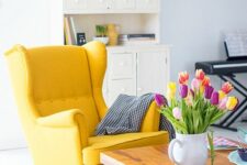 a yellow Standmon chair with a blanket, a stained coffee table and bold tulips in a jar make the space look bold and cool