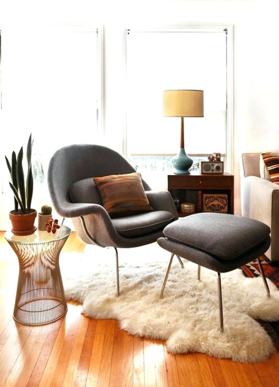 An elegant mid century modern space with a sofa, a sideboard, a grey Wumb chair and ottoman, a side table with plants