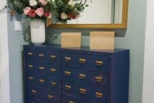 02 a beautiful navy file cabinet as a console table and dresser for a small entryway, with a mirror with a gold frame and blooms