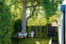 03 a small and dreamy backyard with living walls, a large tree, grass, a hammock and a swing, with a wooden deck
