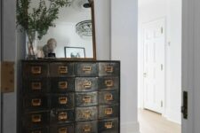 04 a dark-stained shabby chic card cabinet, a mirror and greenery on it adds vintage chic to the entryway and makes it refined