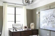 05 a farmhouse home office with olive green paneling, a dark-stained desk and a creamy chair, a geometric pendant lamp