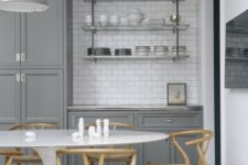 07 a grey farmhouse kitchen with a white subway tile backsplash, a suspended glass shelf, an oval table and stained chairs