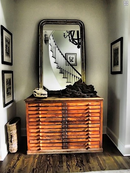 A vintage stained file cabinet with a large mirror in a chic frame and some unusual decor will make your entryway wow
