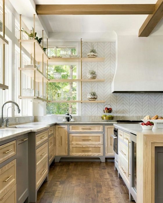 A light stained farmhouse kitchen with shaker cabinets, a large hood, suspended shelves and a kitchen island