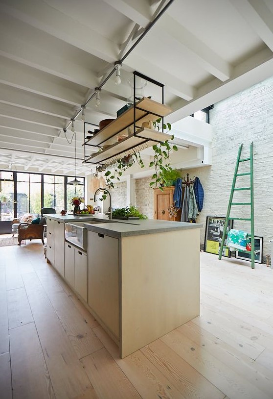 A modern light stained plywood kitchen with suspended shelves, a skylight and lots of greenery