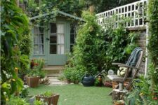 17 a small and narrow garden with a green lawn, greenery and shrubs, potted plants and a chair with a side table