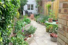 18 a long and narrow garden clad with stone, with raised garden beds with bold blooms and greenery is a lovely space