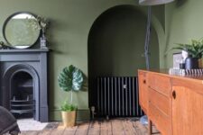 21 a vintage olive green living room with a non-working fireplace, a niche with a credenza, a stained sideboard, a grey floor lamp and a mirror